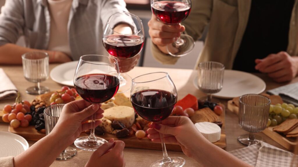 Couples raising glasses of red wine during a French wedding feast — a reason to get married in France and enjoy its cuisine and culture.