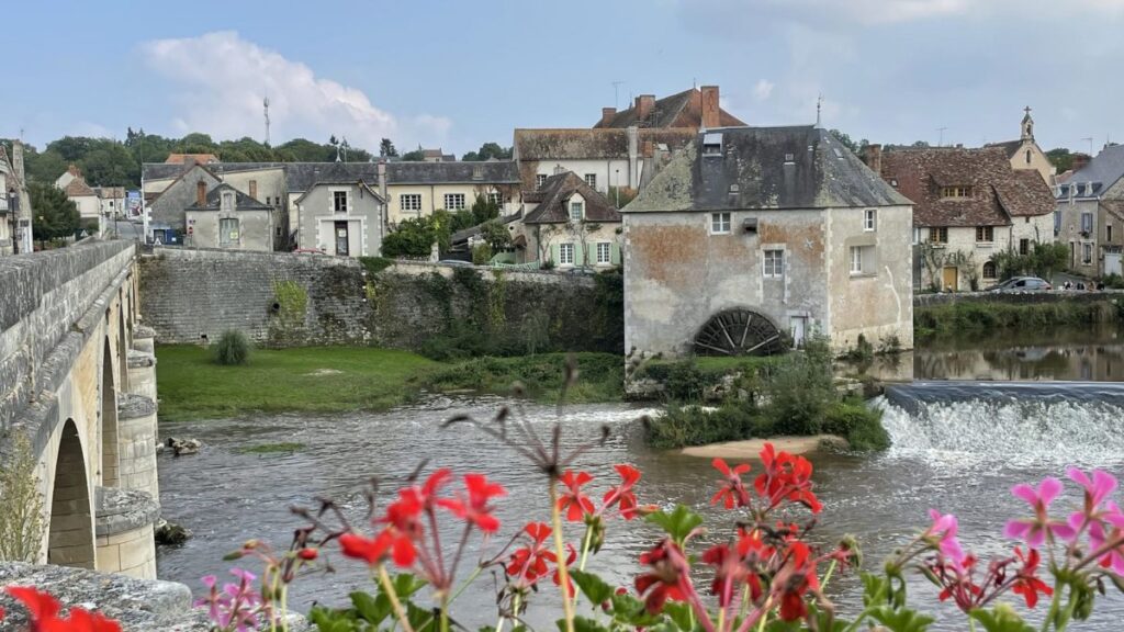 A peaceful French riverside village with stone houses and flowers, capturing a timeless beauty.