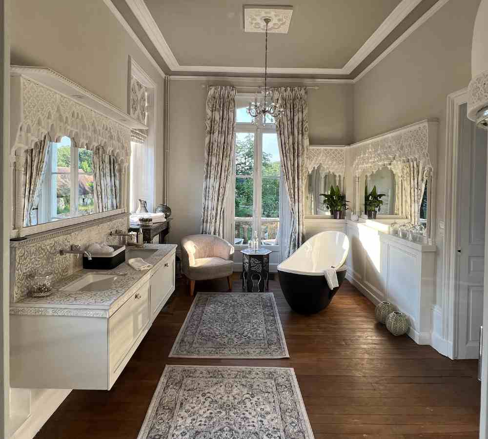 Elegant bridal bathroom with freestanding bath and chandeliers, ideal for romantic escapes at Château de la Boutinière.