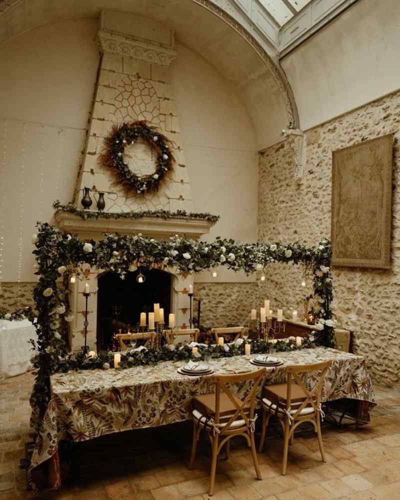 Elegant stone hall with a long decorated table, candles, and greenery, prepared for a micro wedding venue experience inside Château de la Boutinière.