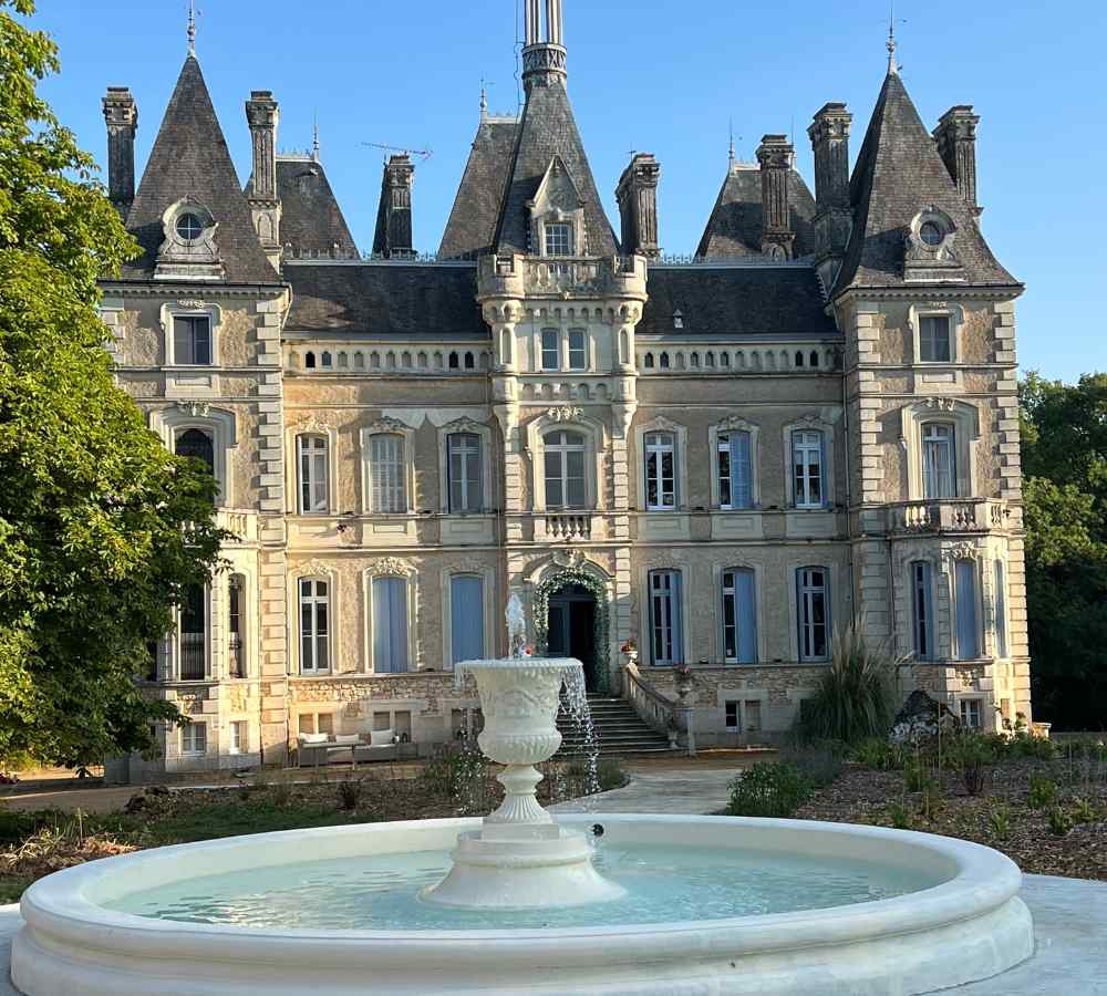 Front view of Château de la Boutinière, with a stone fountain in the foreground, set up as a refined micro wedding venue in the French countryside.