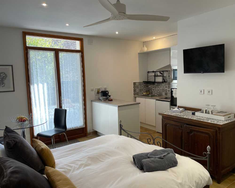Gîte bedroom at Château de la Boutinière with double bed, kitchenette, dining area and glass doors to the garden