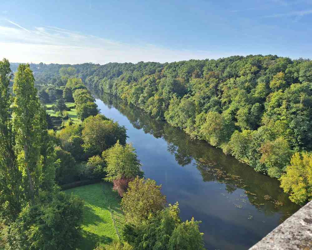 Wide view of a winding river cutting through forested countryside, seen from above in the surrounding area near Château de la Boutinière