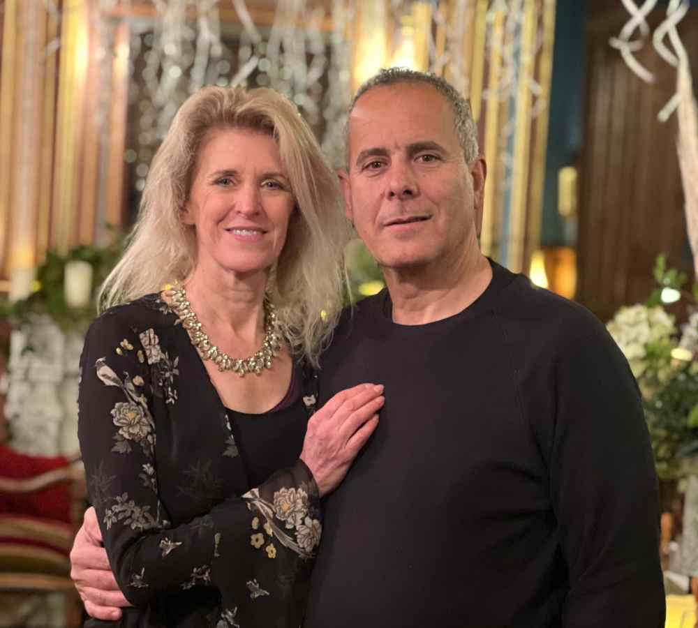 Alison and Zion from Château de la Boutinière standing together inside the château, surrounded by elegant décor and warm evening lighting.