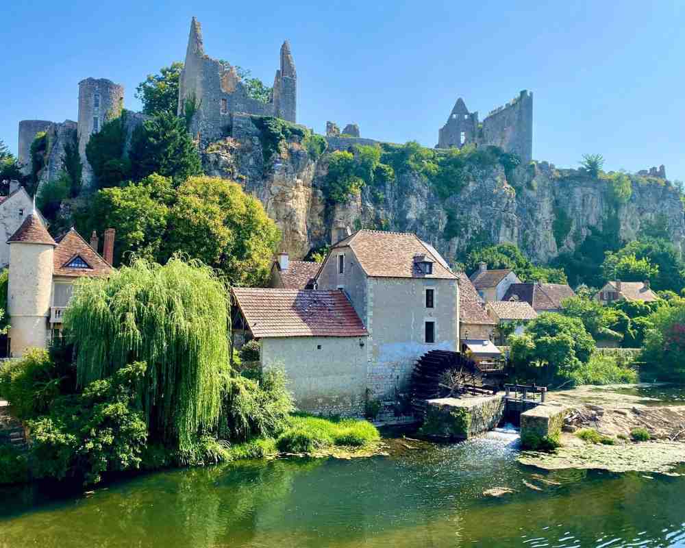 Château stays in France exploring historic villages and riverside scenery near Château de la Boutinière, showing traditional stone houses beneath a medieval hilltop château.