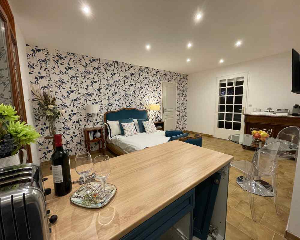 Spacious gîte-style suite with modern kitchen island, double bed, and seating area at Château de la Boutinière, providing relaxed accommodation within a refined micro wedding venue setting.