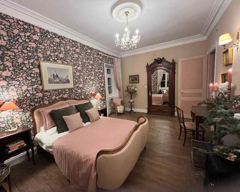 Elegant guest bedroom with floral wallpaper, soft pink furnishings, and antique details at Château de la Boutinière, part of the accommodation offered at this intimate micro wedding venue.