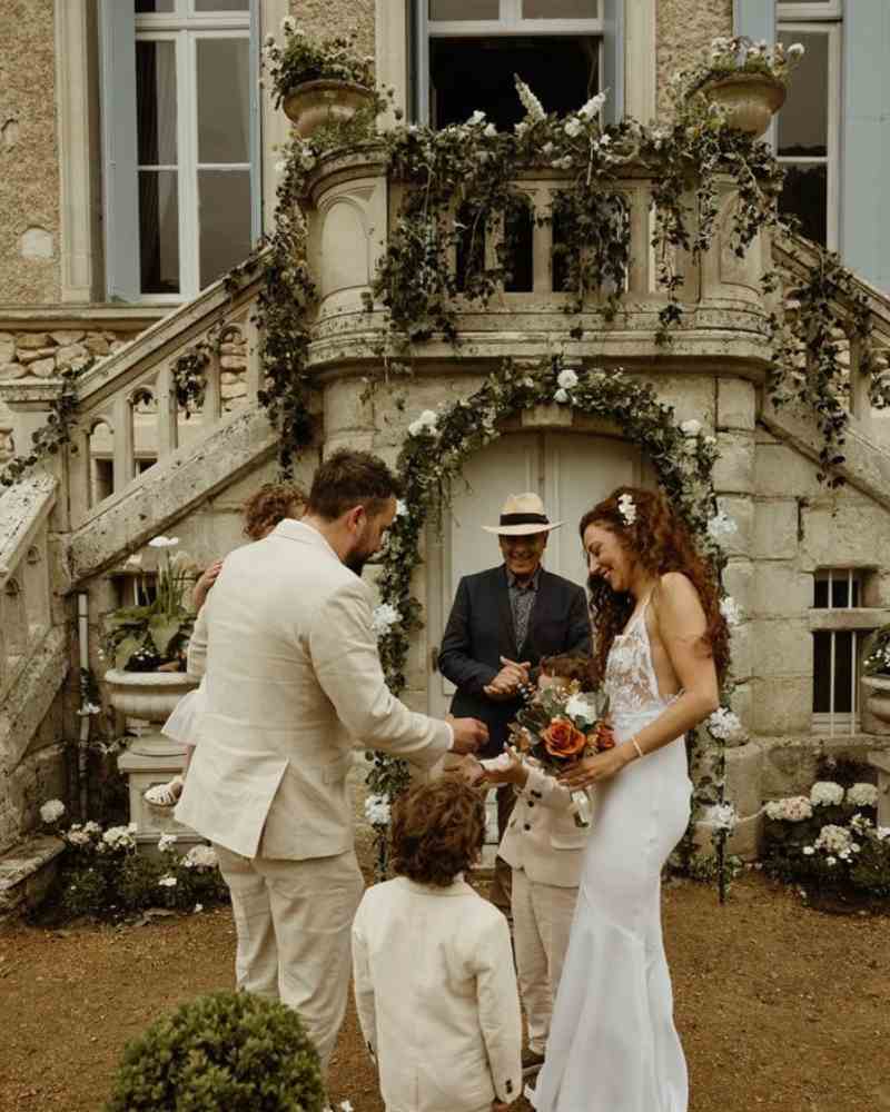 Wedding ceremony with a couple and their children in the courtyard of Château de la Boutinière, surrounded by floral décor at a micro wedding venue in France.