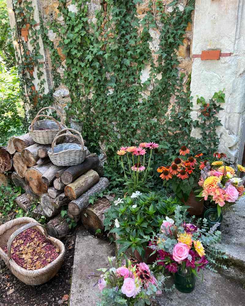 Seasonal floral arrangements and rustic details against an ivy-covered stone wall at Château de la Boutinière, creating a natural setting for a micro wedding in France.