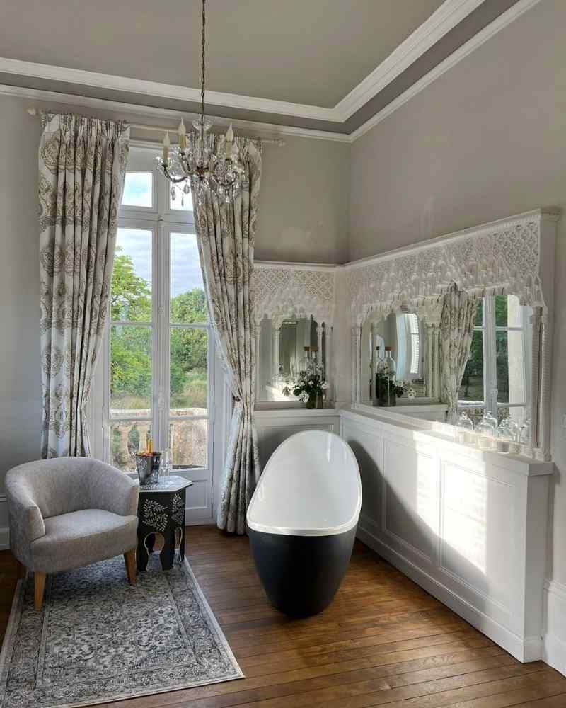 Bridal suite bathroom at Château de la Boutinière with freestanding bath, chandelier and patterned curtains supplied by Curtains Made Simple.