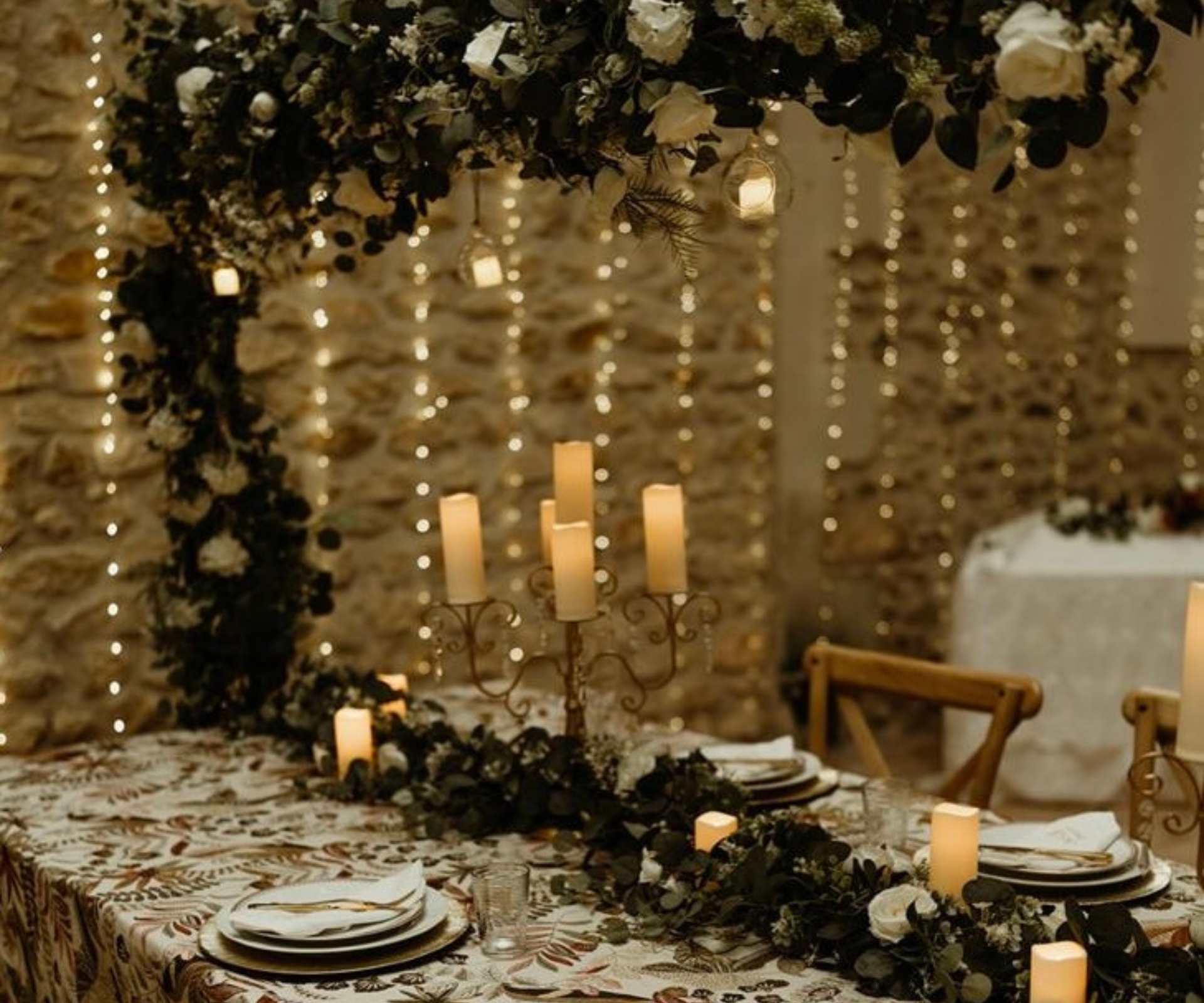Candlelit table setting inside a stone venue at Château de la Boutinière, styled for an intimate private event venue in France.
