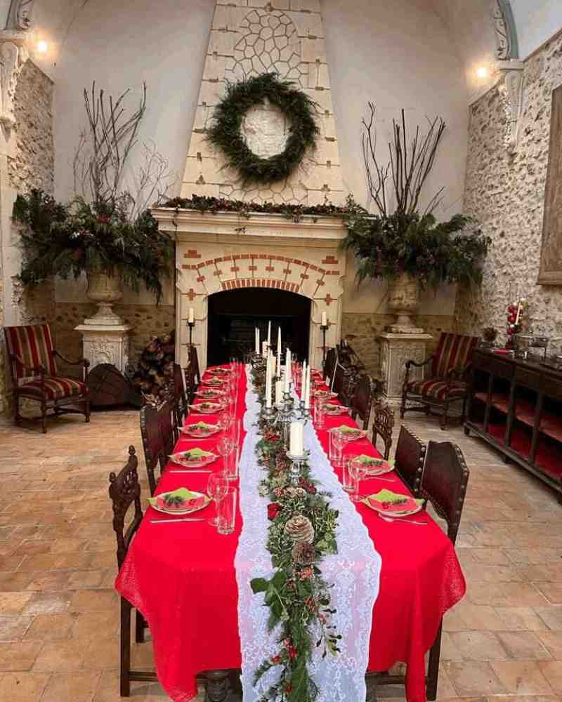 Long banquet table set with red linens and candles inside Chateau de la Boutinière, showcasing the dining space of a private event venue.
