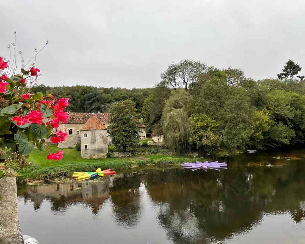 River beside the château grounds with colourful kayaks and historic stone buildings, offering a peaceful setting for a château wedding in France