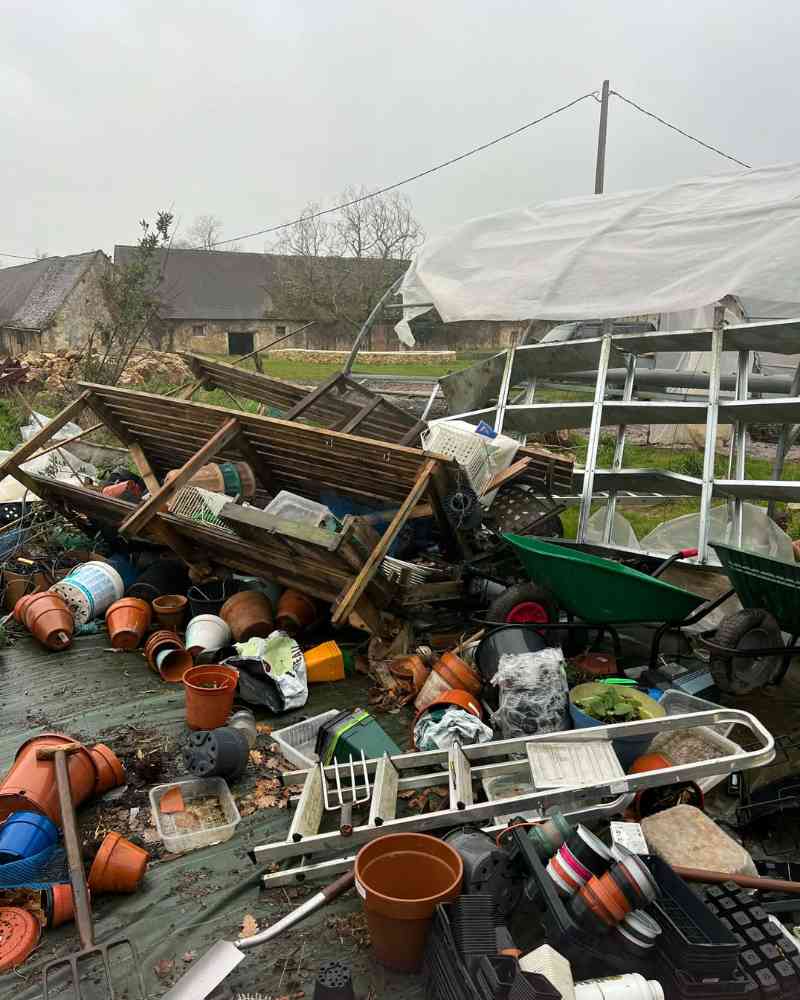 Pots, shelves, tools and garden equipment are strewn across the ground beside the damaged greenhouse after severe storm winds.