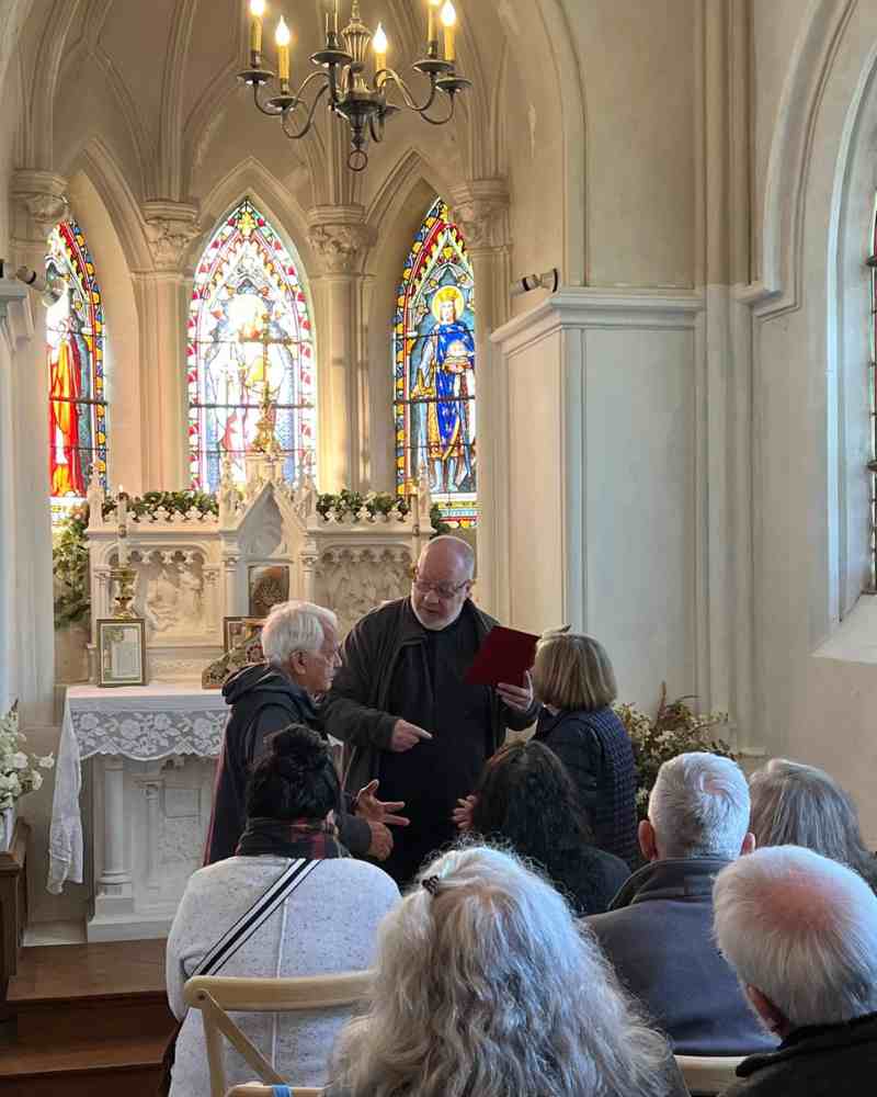 Mary and Leo renew their vows inside the chapel at Château de la Boutinière, standing before the altar with guests seated behind them.