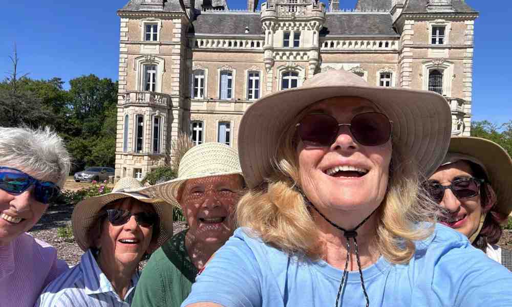 Chateau events gardening day selfie of four smiling women in sun hats with Château de la Boutinière in the background.