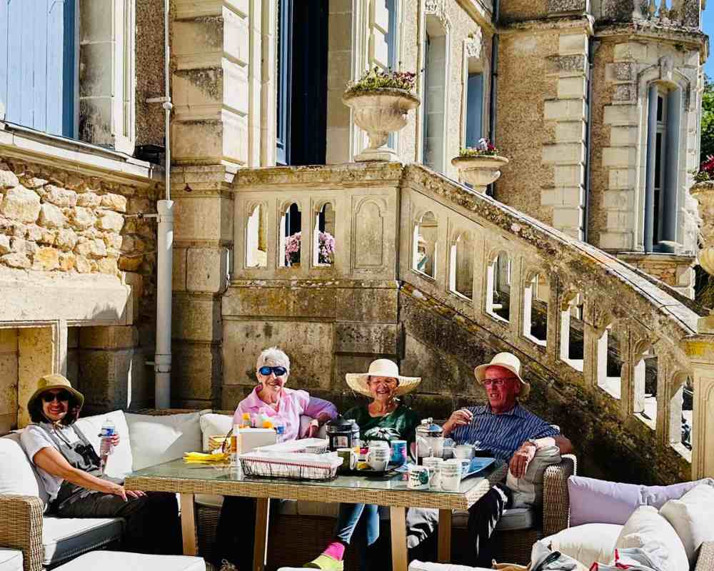 Chateau events gardening day with guests relaxing around a sofa table on the château terrace in bright spring sunshine.