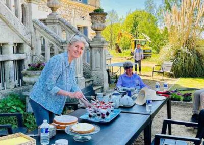 Alison serving cakes and desserts at an outdoor table beside the château steps during Gardening Day at Château de la Boutinière.