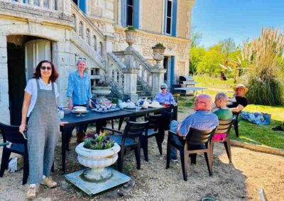 Chateau events gardening day with Alison and guests standing and sitting around the outdoor lunch table beside the château entrance.