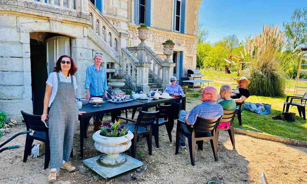 Chateau events gardening day with Alison and guests standing and sitting around the outdoor lunch table beside the château entrance.