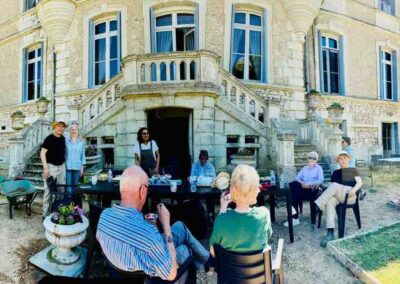Chateau events gardening day with guests sitting together around outdoor tables in front of the château after gardening work.