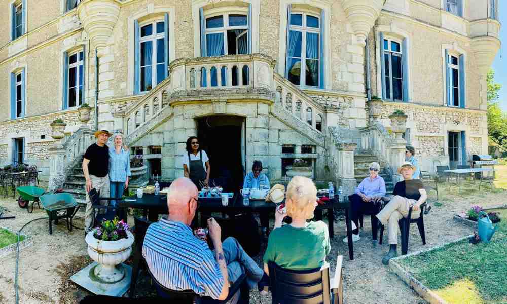 Chateau events gardening day with guests sitting together around outdoor tables in front of the château after gardening work.