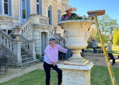 Chateau events gardening day with two women planting flowers into a large stone urn in front of the château.