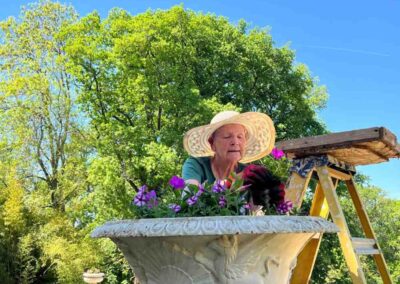 Chateau events gardening day close view of a woman planting bright pink and purple flowers into a large stone urn.