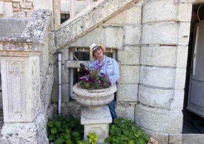 Chateau events gardening day with a smiling guest standing beside a planted stone urn at the château entrance.
