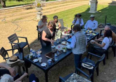 Chateau events gardening day lunch scene with guests seated outdoors beside the château enjoying drinks, cakes and conversation.