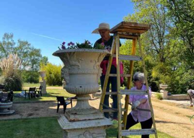 Chateau events gardening day with guests and hosts gathered around outdoor tables in front of the château during a break from garden work.
