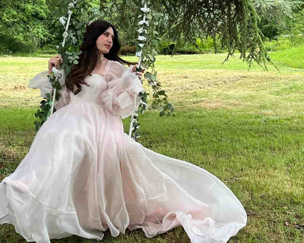 Doreen seated on a flower-decorated swing in the gardens at Château de la Boutinière.